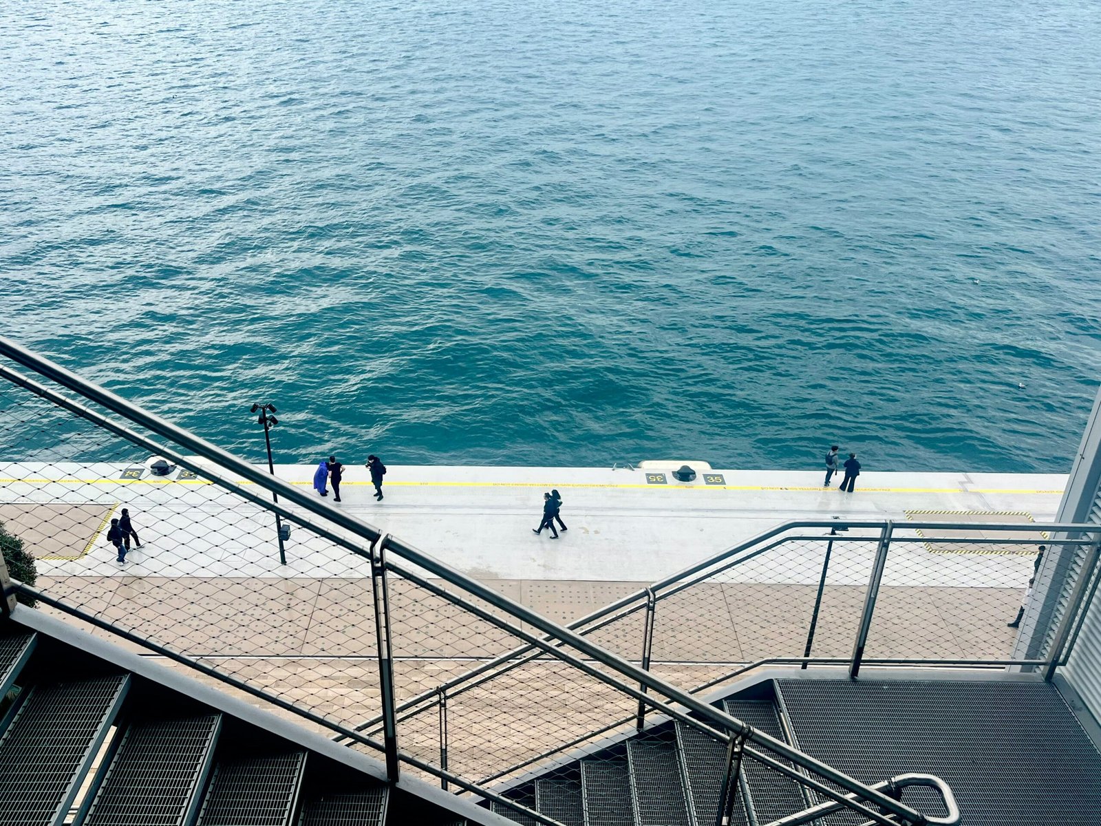 a group of people walking down a flight of stairs next to the ocean